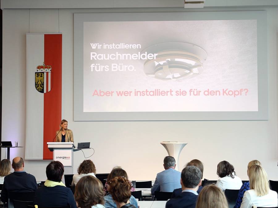 Frau zeigt Publikum eine Präsentation zum Thema Gesundheit im Beruf